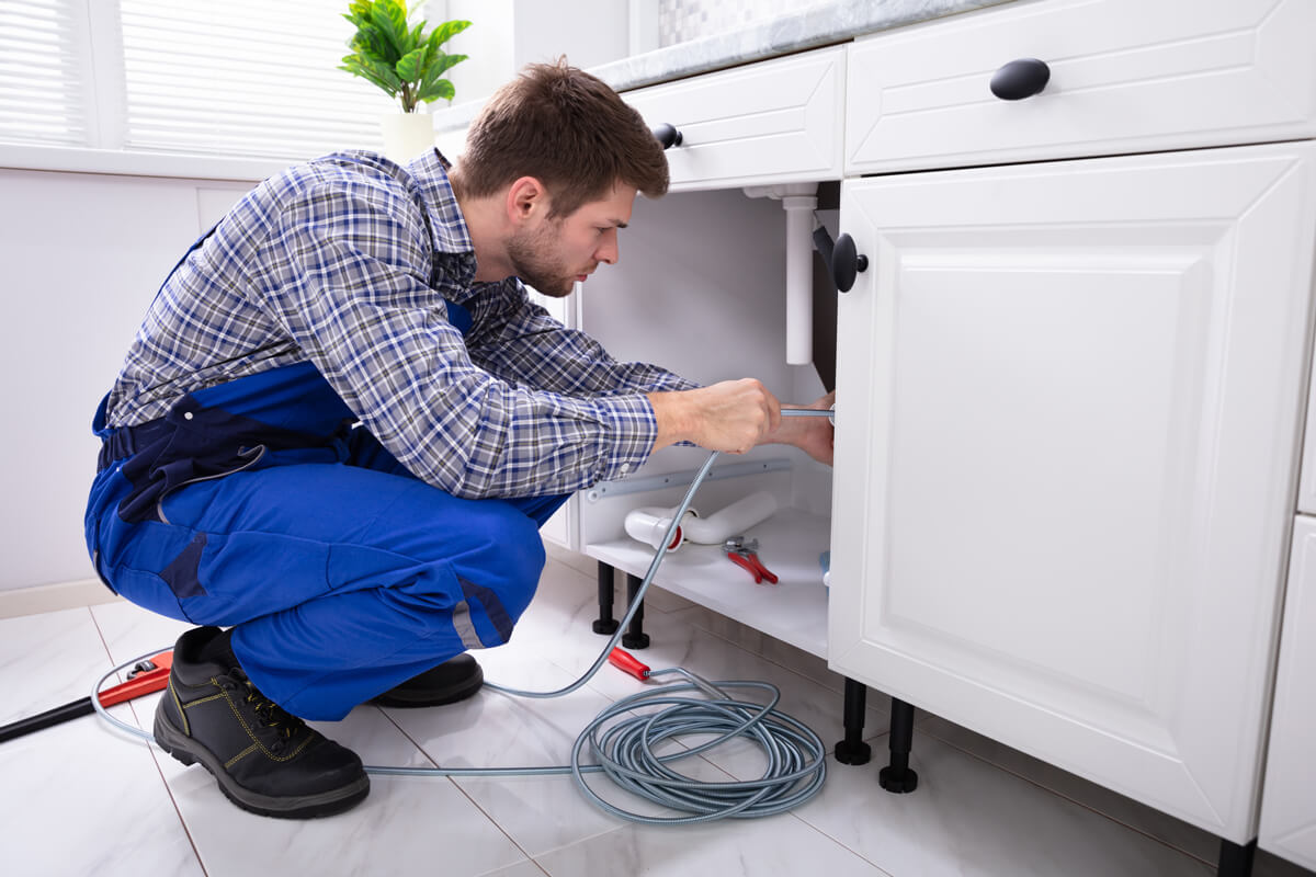 Young Male Plumber Cleaning Clogged Pipe