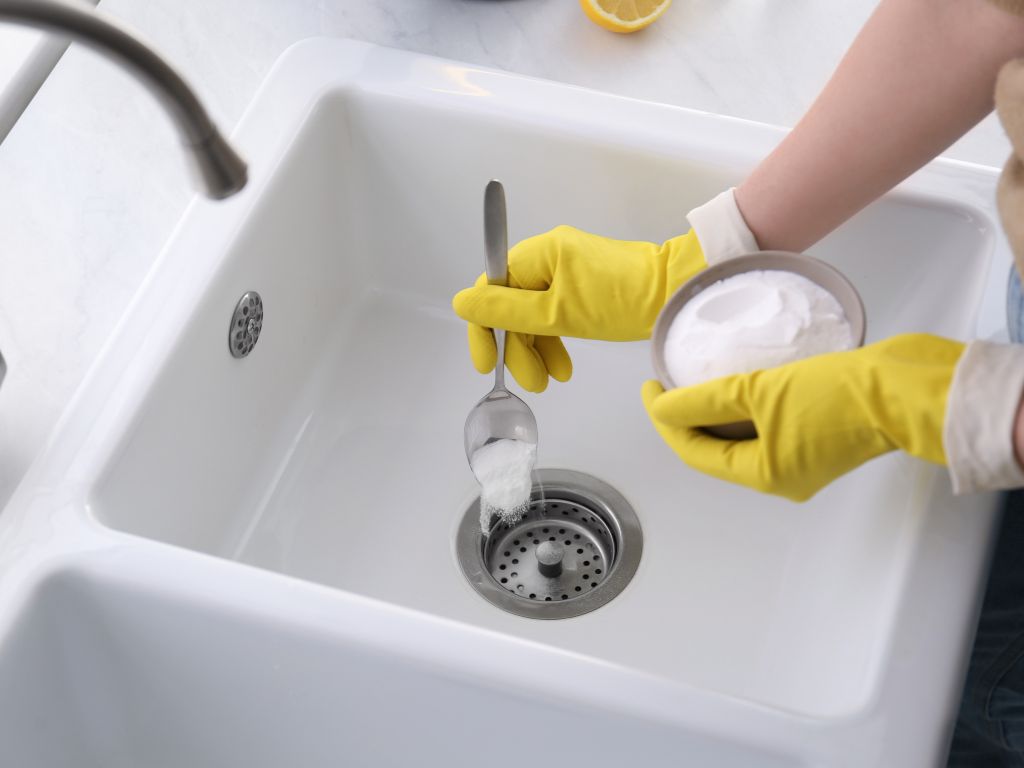 Get Rid of Stinky Drains: Make Your House Smell Clean Again 4 woman putting baking soda to sink drain