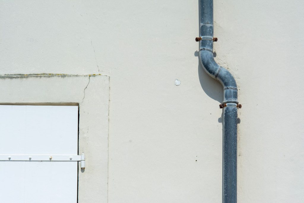 A gray metal drainpipe attached to a plain exterior wall in Chicago